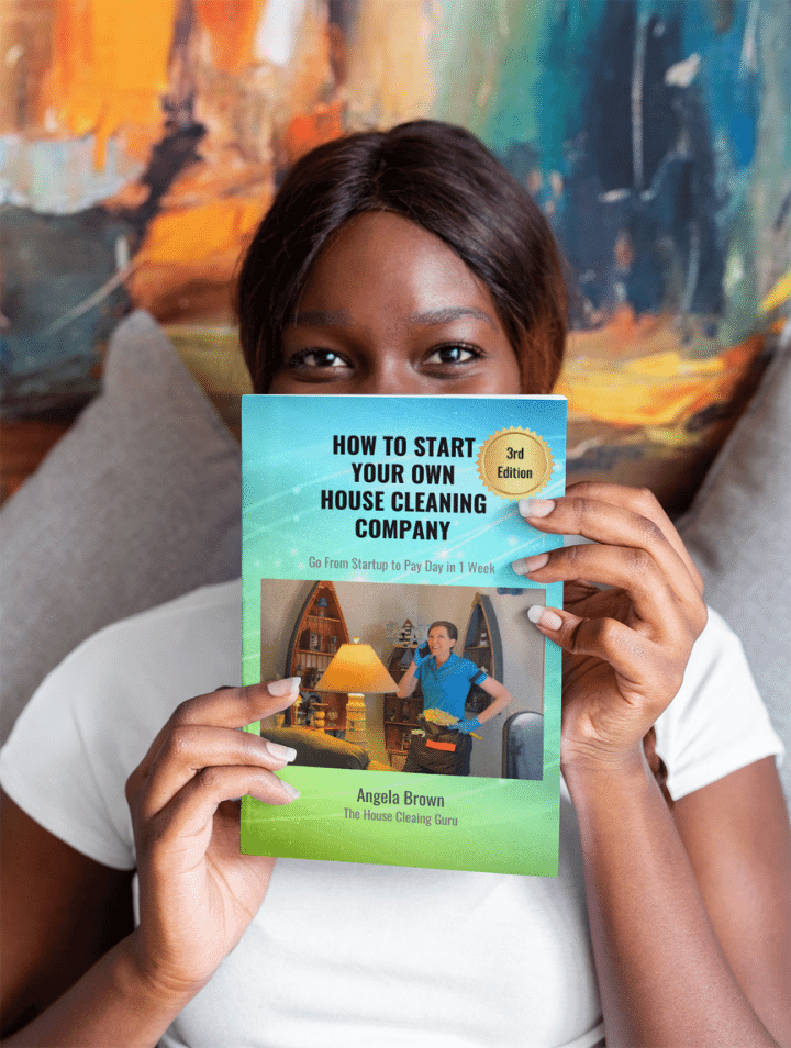 Woman holding up new version of Angela Browns House Cleaning Book